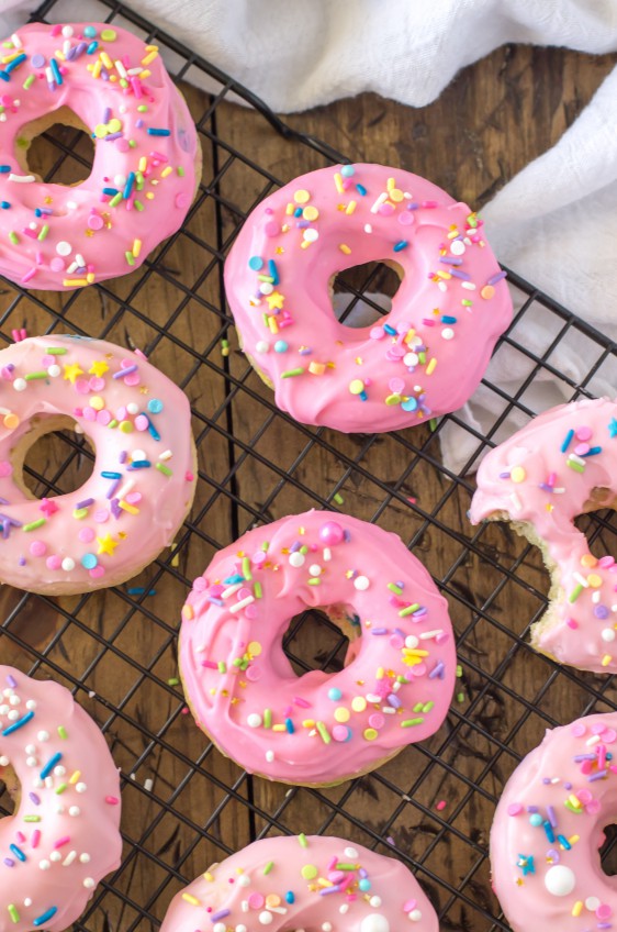 These Baked Funfetti Doughnuts are light, fluffy, crammed with sprinkles, and covered in a pretty pink glaze (and more sprinkles!) by @SugarSpunRun