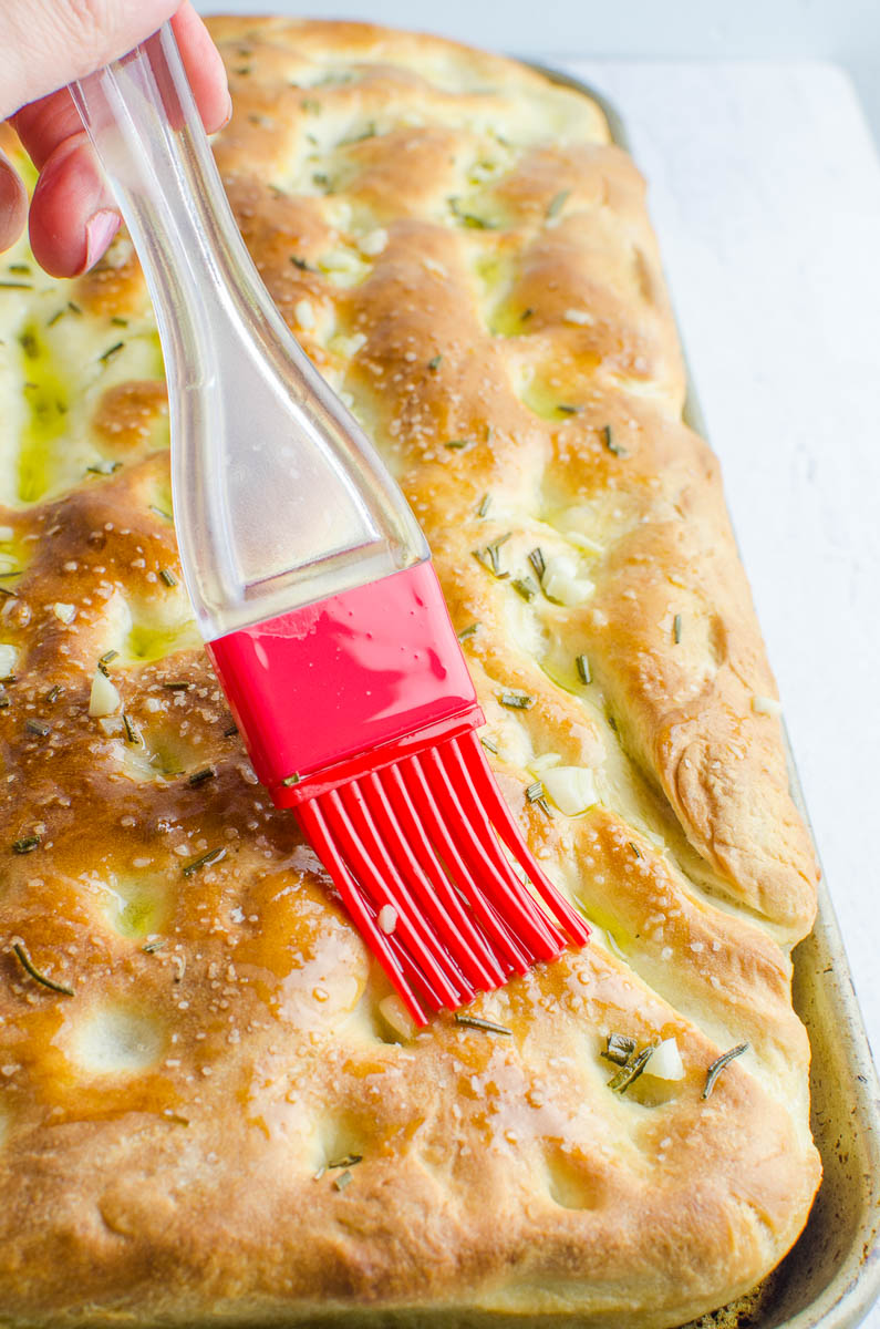 Red pastry brush, brushing garlic oil over focaccia bread. 