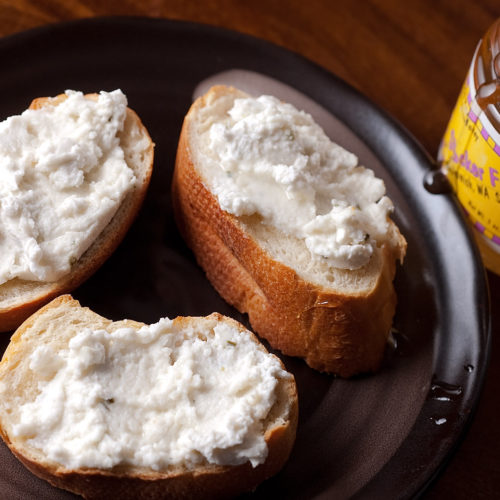 goat cheese and honey crostini on black plate.