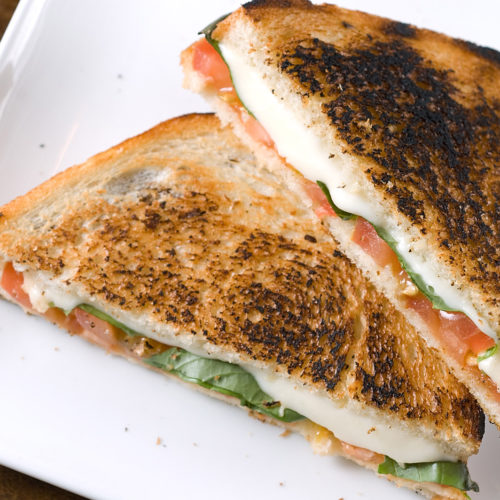 Grilled caprese sandwich on white plate.