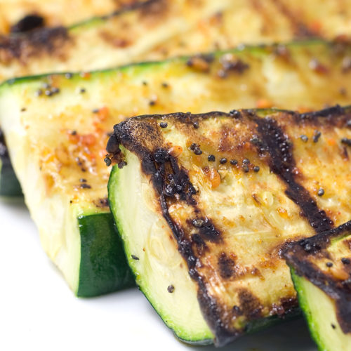 sliced grilled zucchini on white plate.