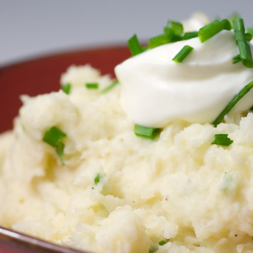 Close up of horseradish mashed potatoes topped with sour cream and chives.