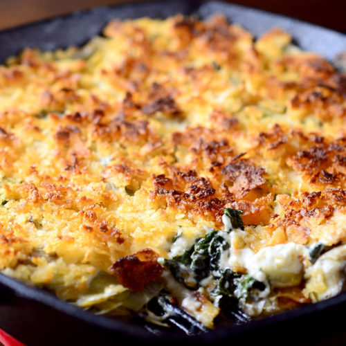 hot kale and artichoke dip in a pan.