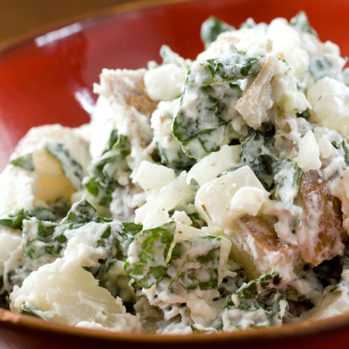 Kale and potato salad in red bowl.