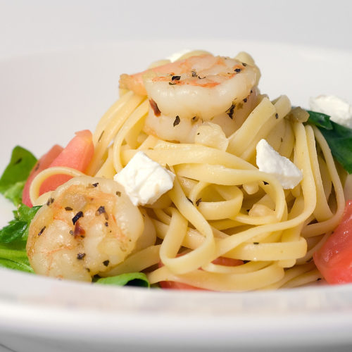 Bowl of linguine with prawns, spinach and tomatoes.