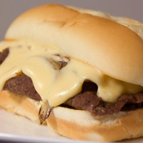 Philly cheesesteak sandwich on plate.