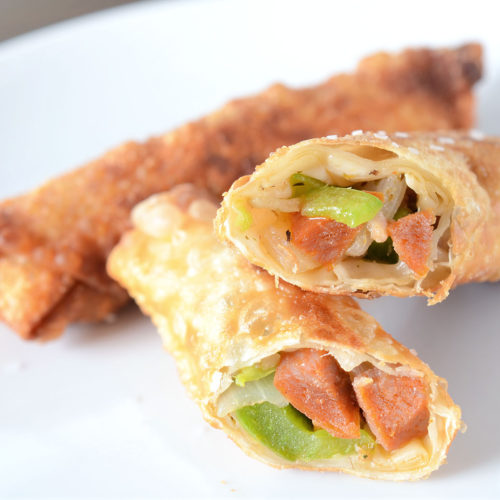 two pizza egg rolls on white plate.