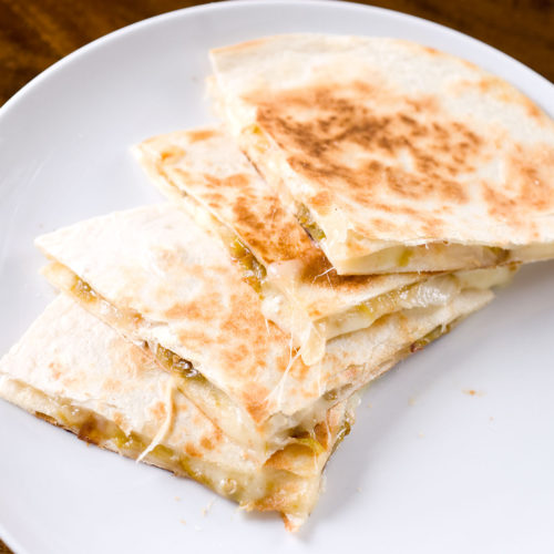 sliced hatch chile quesadilla on white plate.
