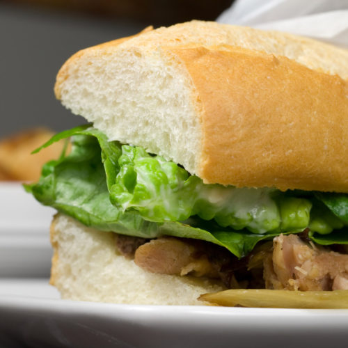 Roasted pork sandwich on white plate.