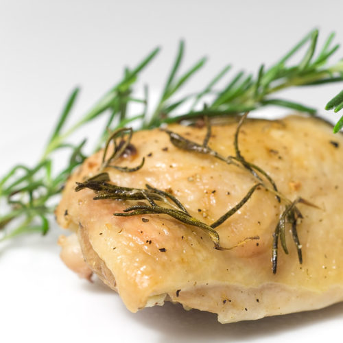 Roasted rosemary chicken thighs on white plate.