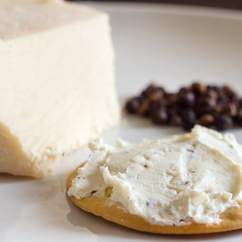 romano and black pepper spread on cracker.