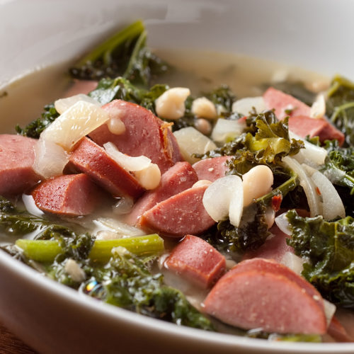 Sausage and white bean soup in white bowl