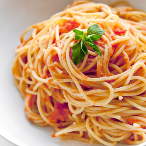 Spaghetti with creamy marinara in white bowl.