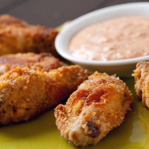 Spiced chicken wings on yellow plate.