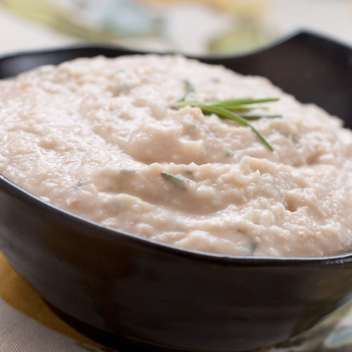 white bean and rosemary hummus in black bowl.