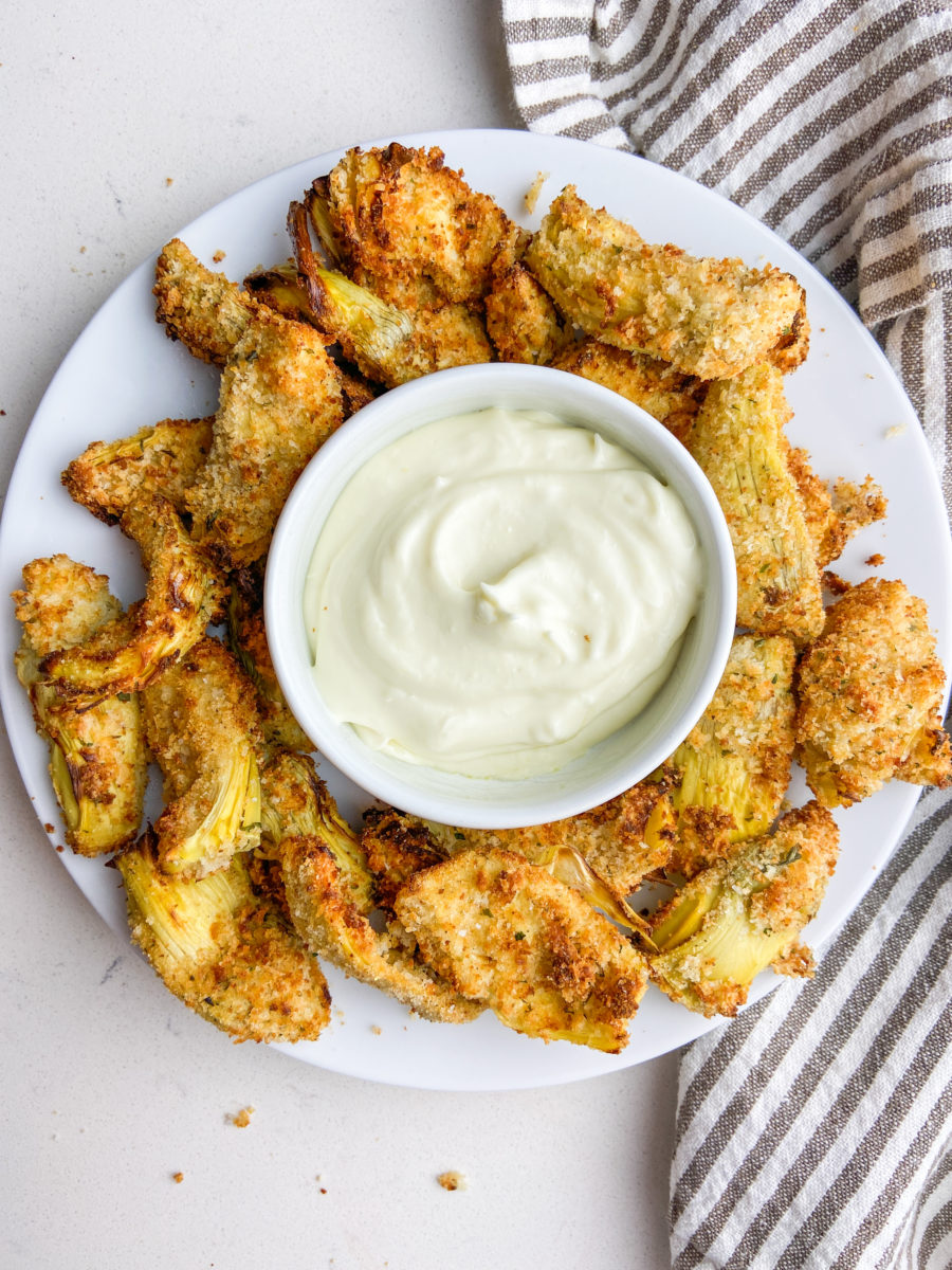 Overhead photo of fried artichokes on a white plate with garlic aioli 