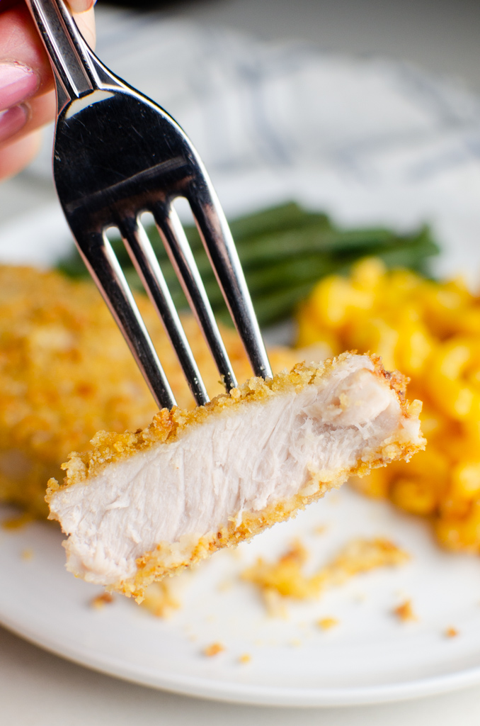 A bite of pork chop on a fork. 