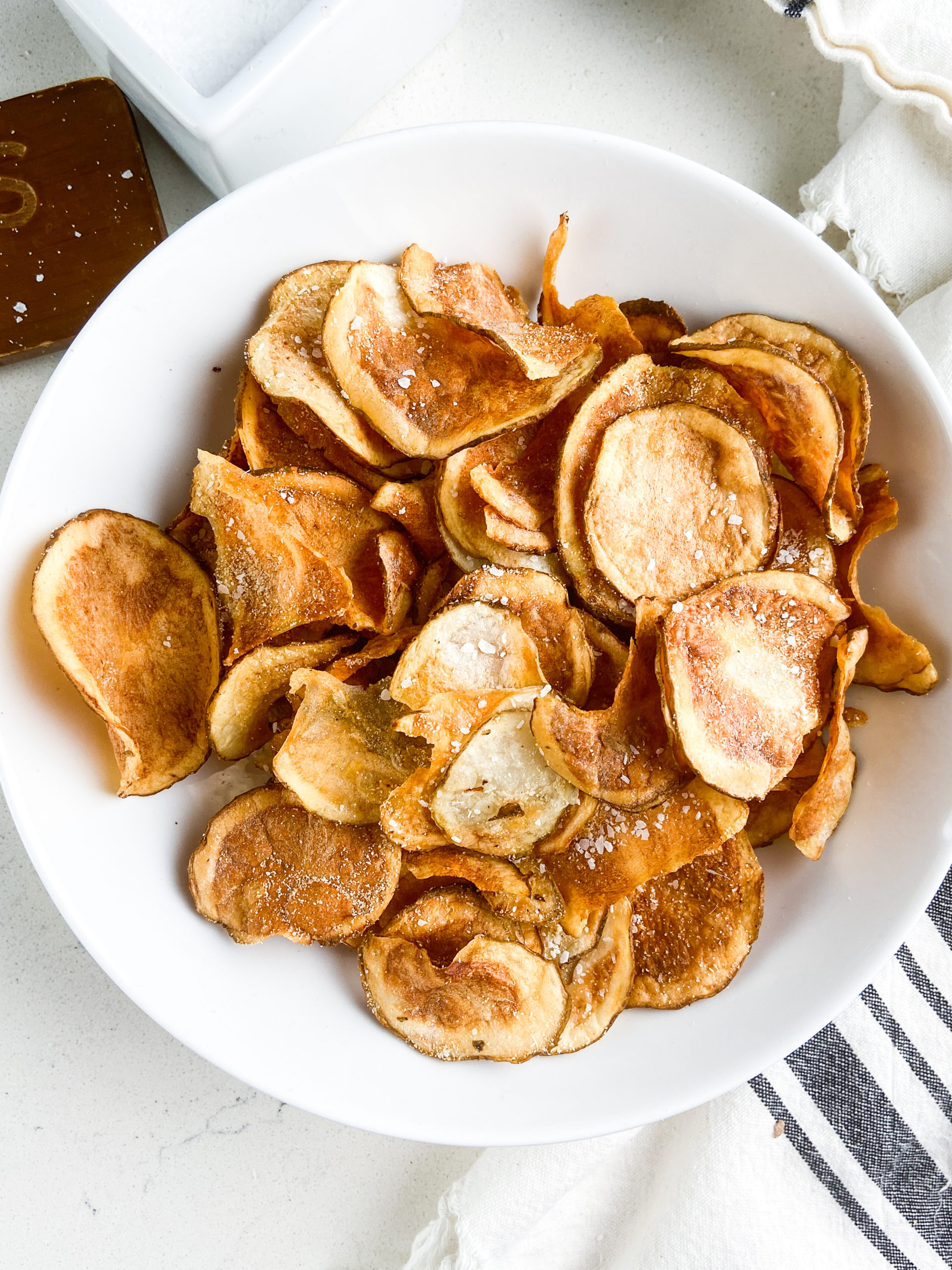 Overhead photo of air fryer potato chips in a white bowl. 
