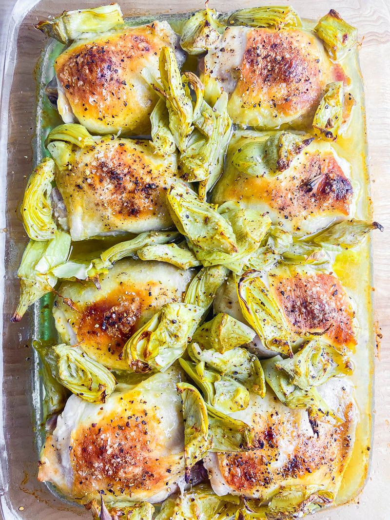 Overhead photo of chicken and artichokes in glass baking dish. 