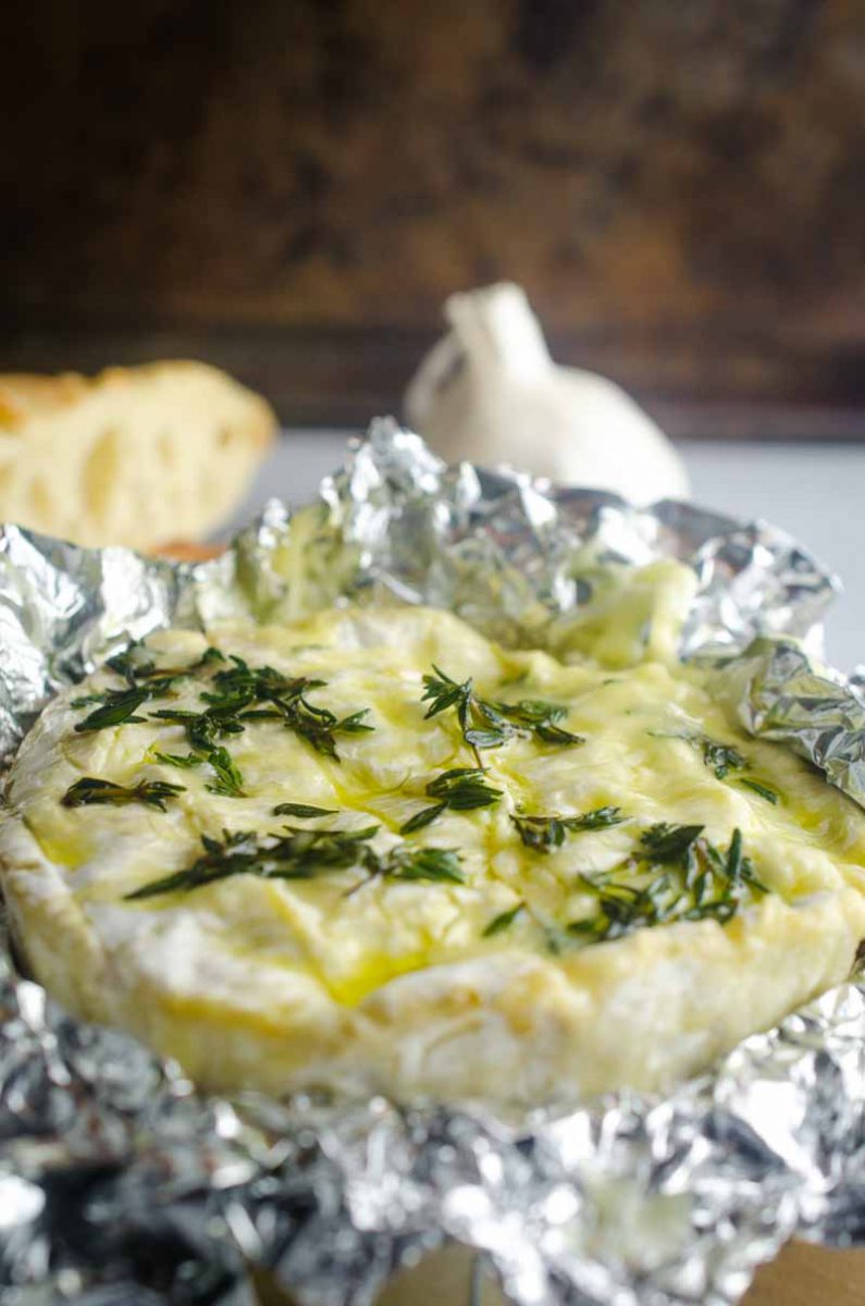 Baked camembert cheese studded with fresh garlic, thyme and a drizzle of olive oil. It's a cheese lover's dream! Serve with crackers and crostini.