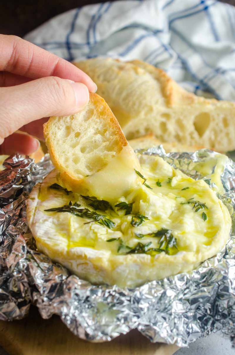 Baked camembert cheese studded with fresh garlic, thyme and a drizzle of olive oil. It's a cheese lover's dream! Serve with crackers and crostini.