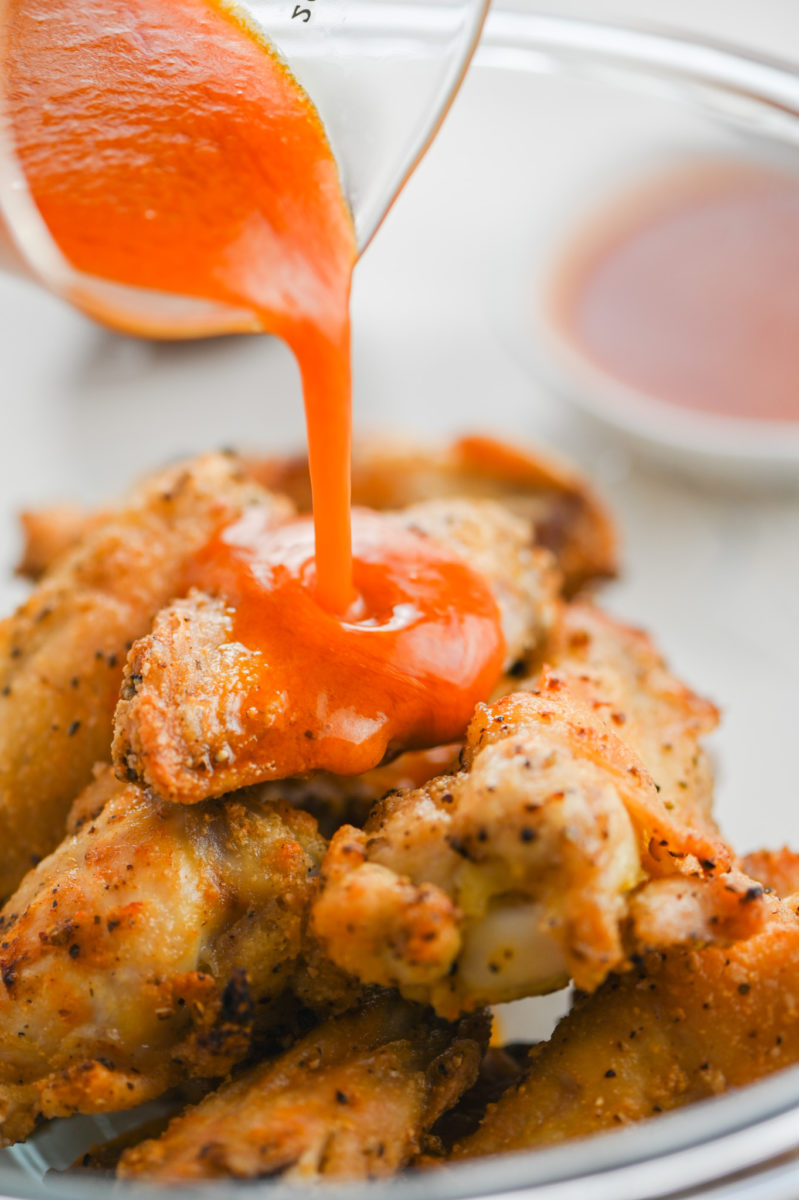 Drizzling buffalo sauce over wings. 
