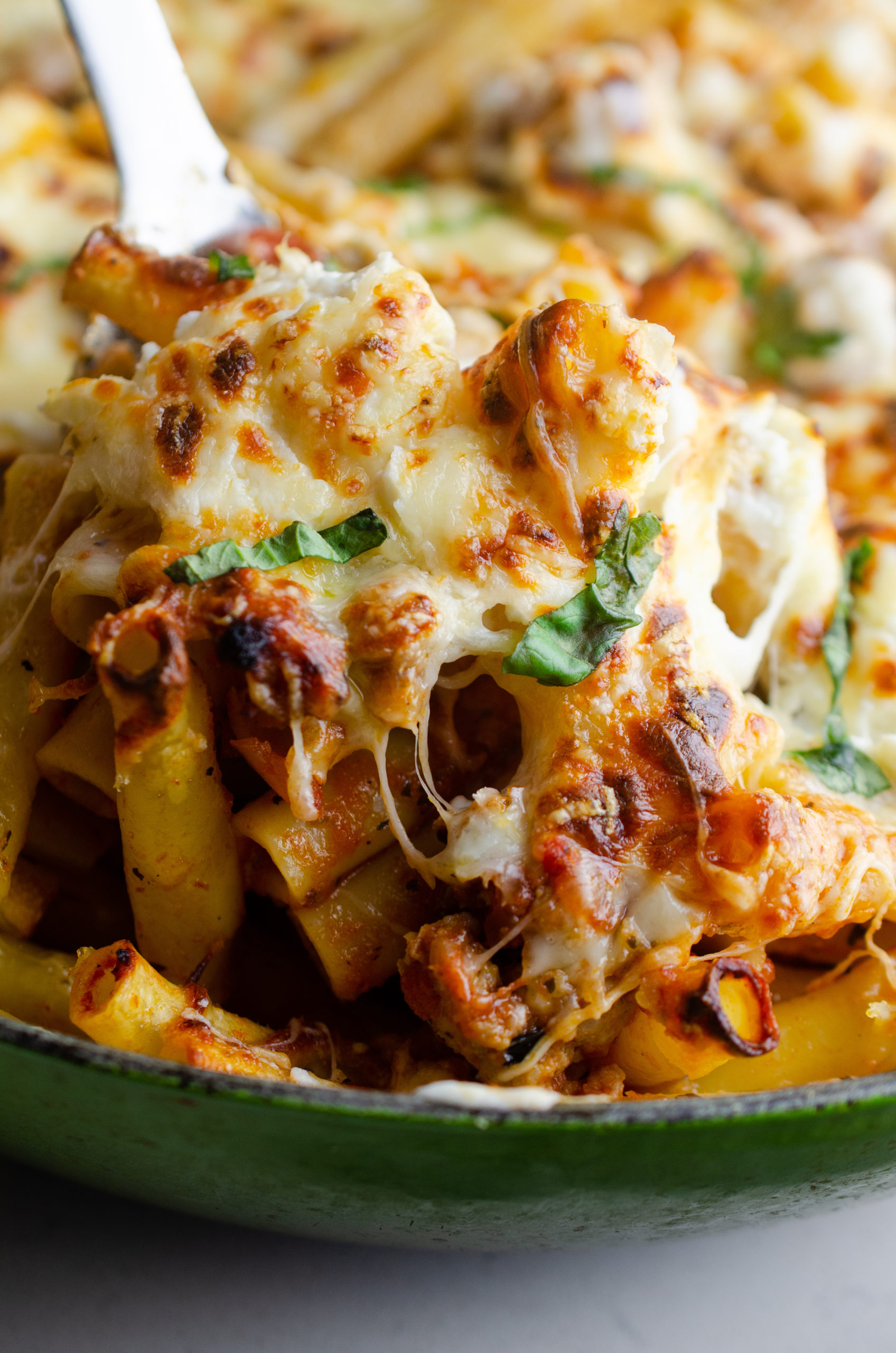 A spoonful of baked ziti with a cheese pull. 
