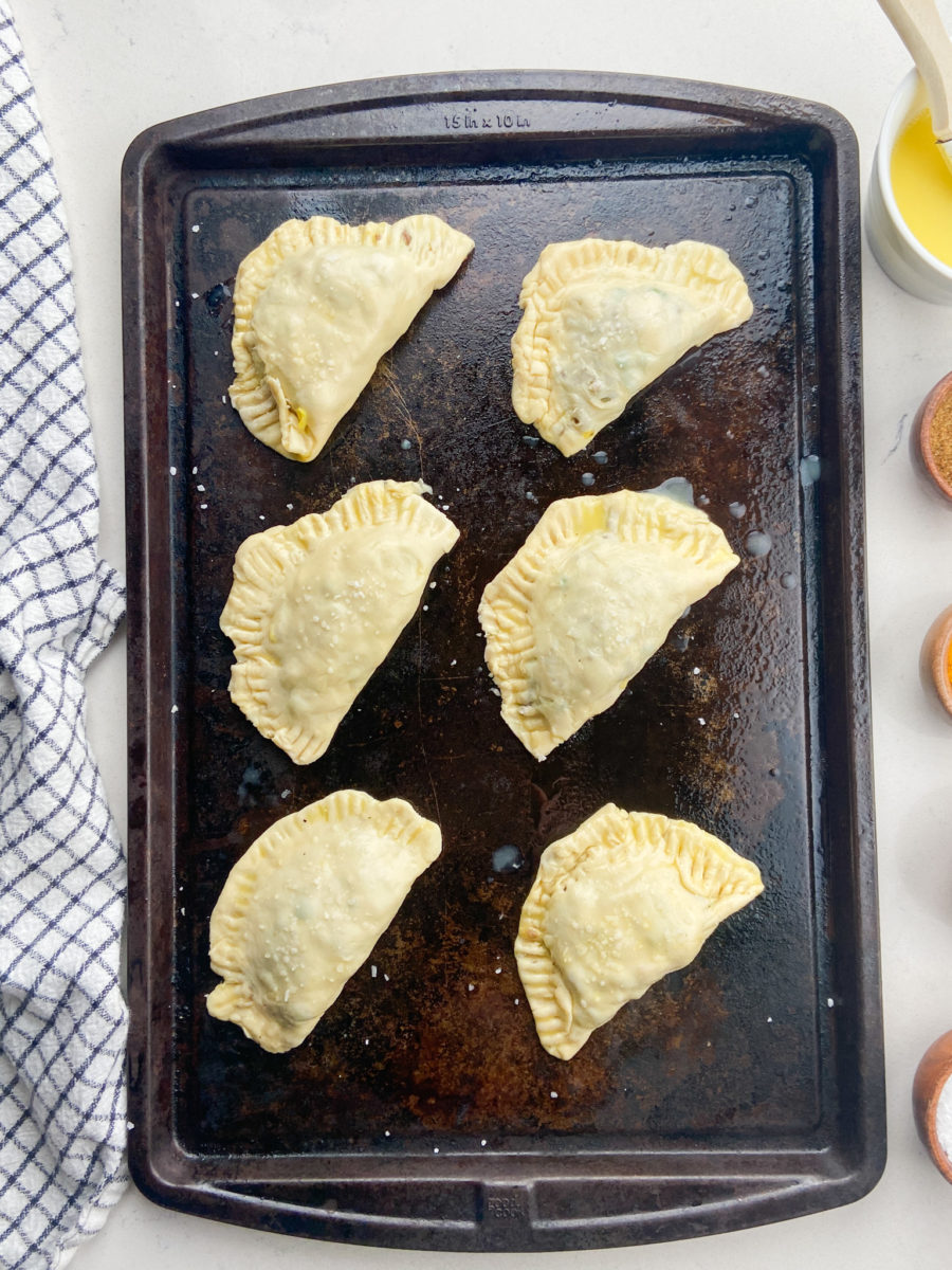 Uncooked beef samosas on baking tray. 