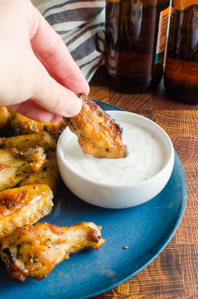 A chicken wing being dipped in ranch dressing. 