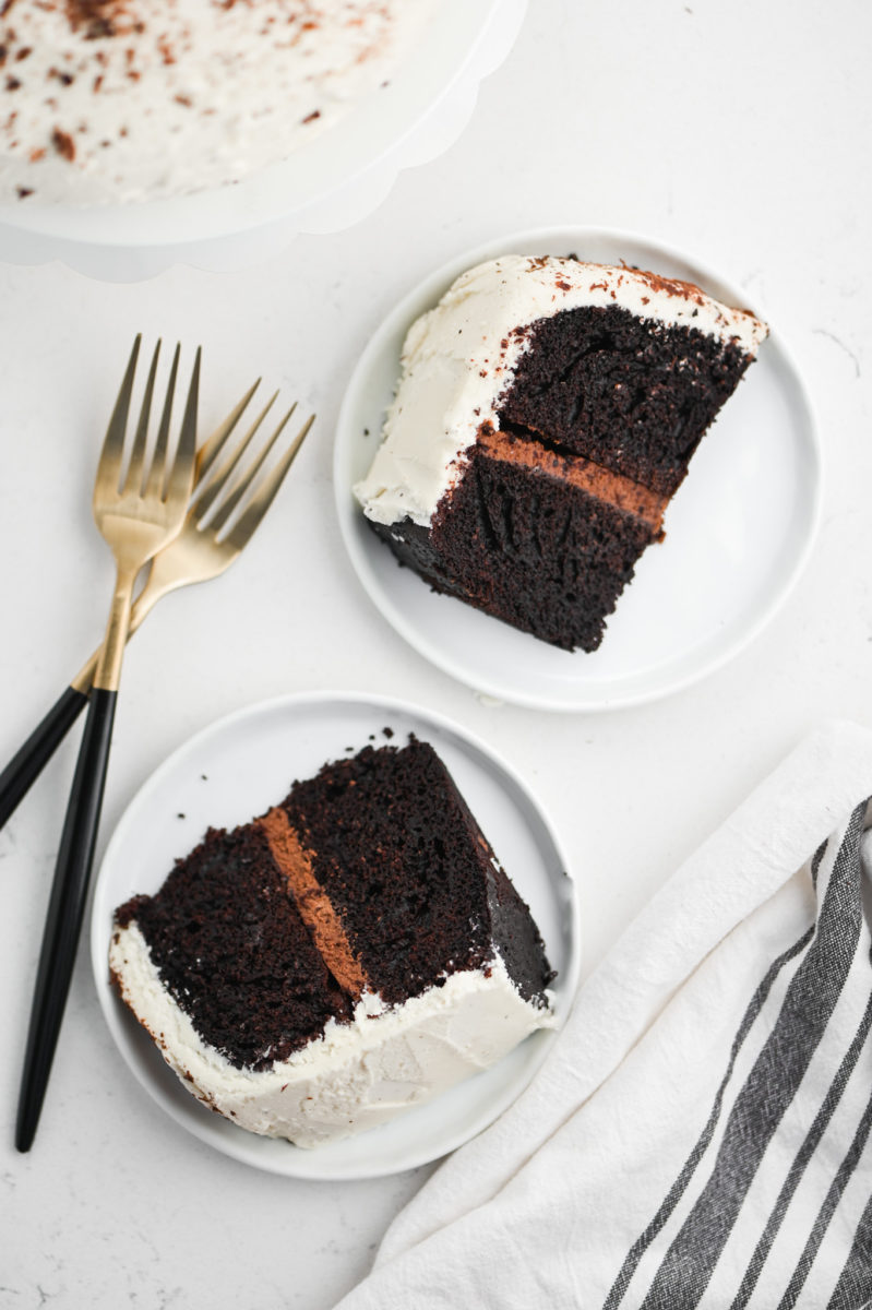 Two slices black and white cake on white plates. 