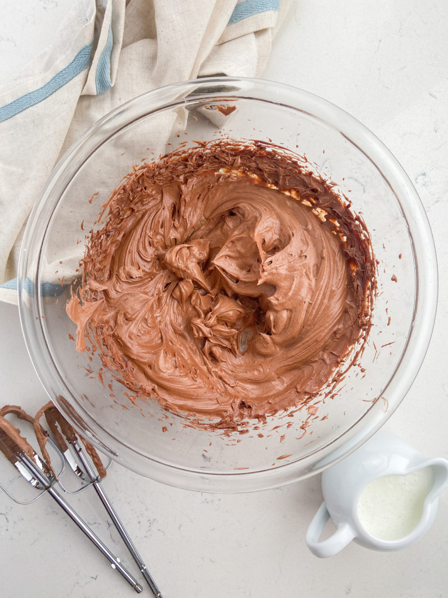 Whipped chocolate ganache frosting in glass bowl.