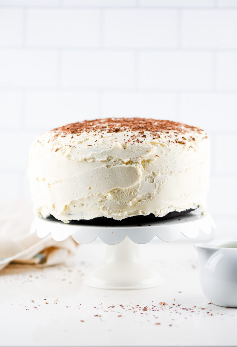 Frosted cake on a white cake stand. 