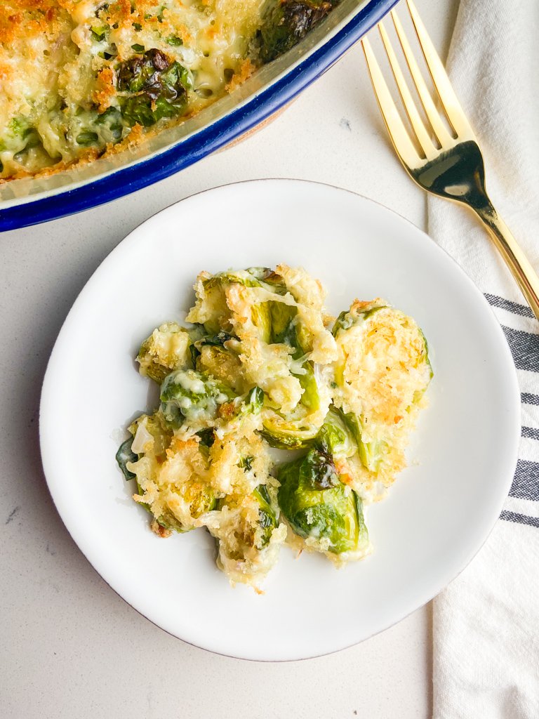 Brussels Sprouts au gratin on a white plate with a gold fork. 