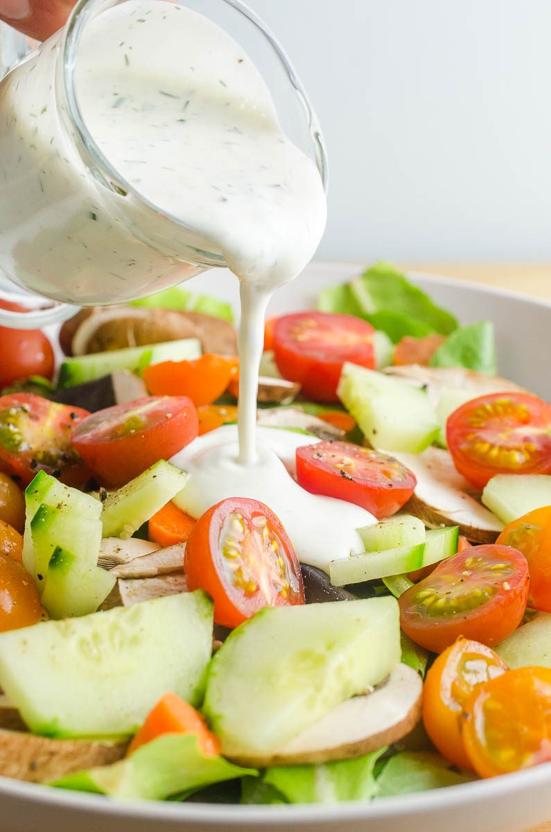 Pouring ranch dressing on a salad. 