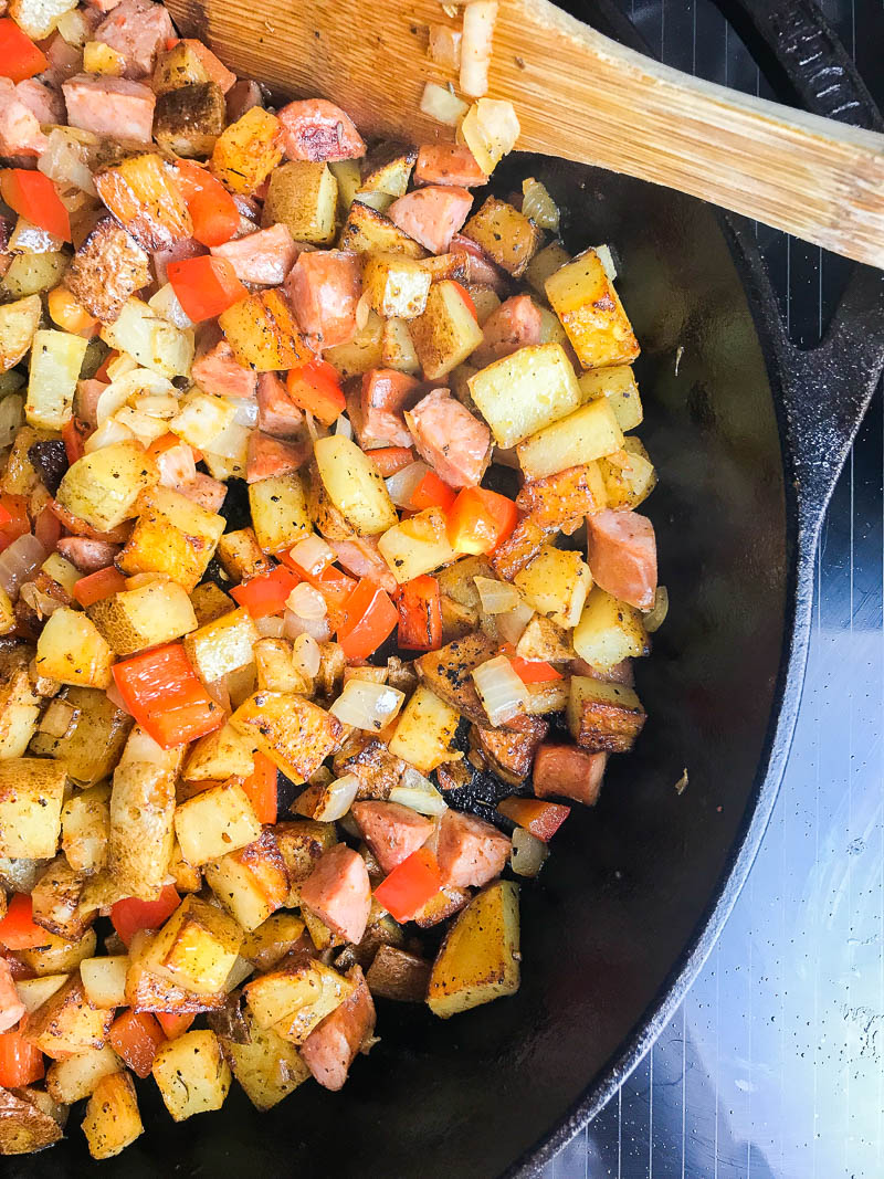 Overhead photo of diced potatoes and vegetables in a skillet. 