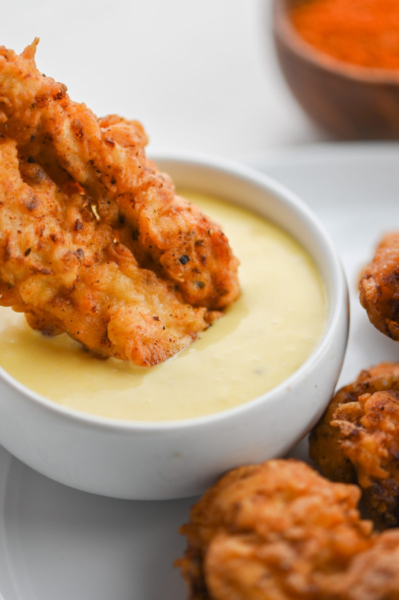 Dipping Cajun Chicken Tender in honey mustard dressing. 