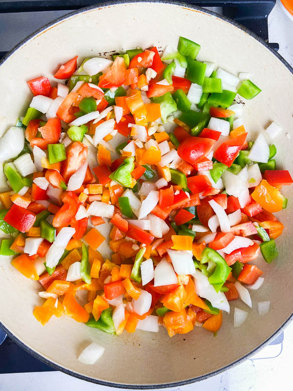 Bell peppers and onions cooking in a skillet. 