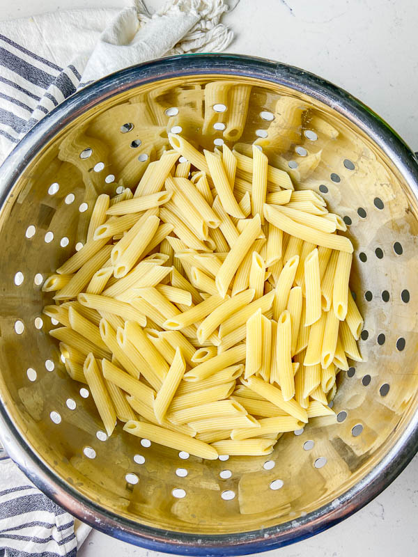 Cooked penne pasta in a colander. 