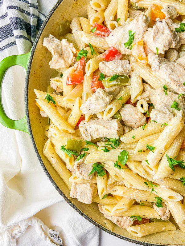 Overhead photo of jerk chicken pasta in a green pan. 