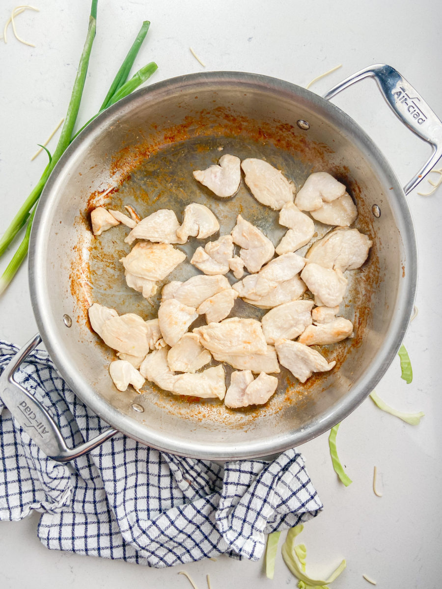 Chicken pieces cooking in stainless steel pan. 