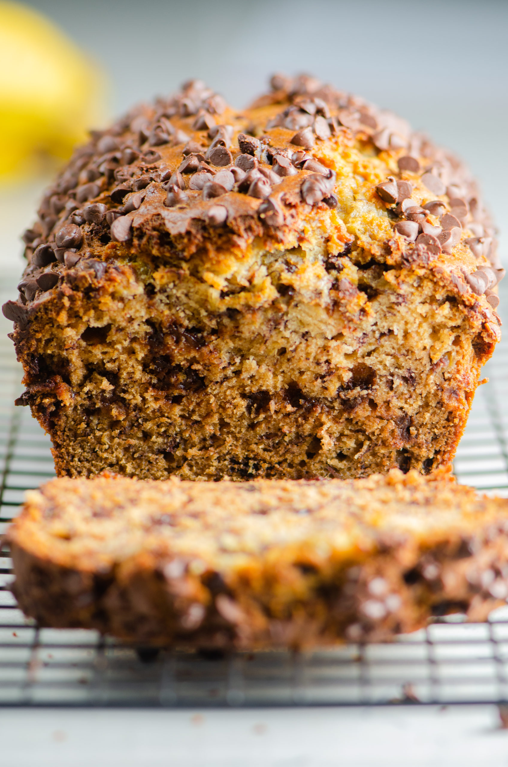 Head on photo of banana bread with a slice laying in front. 