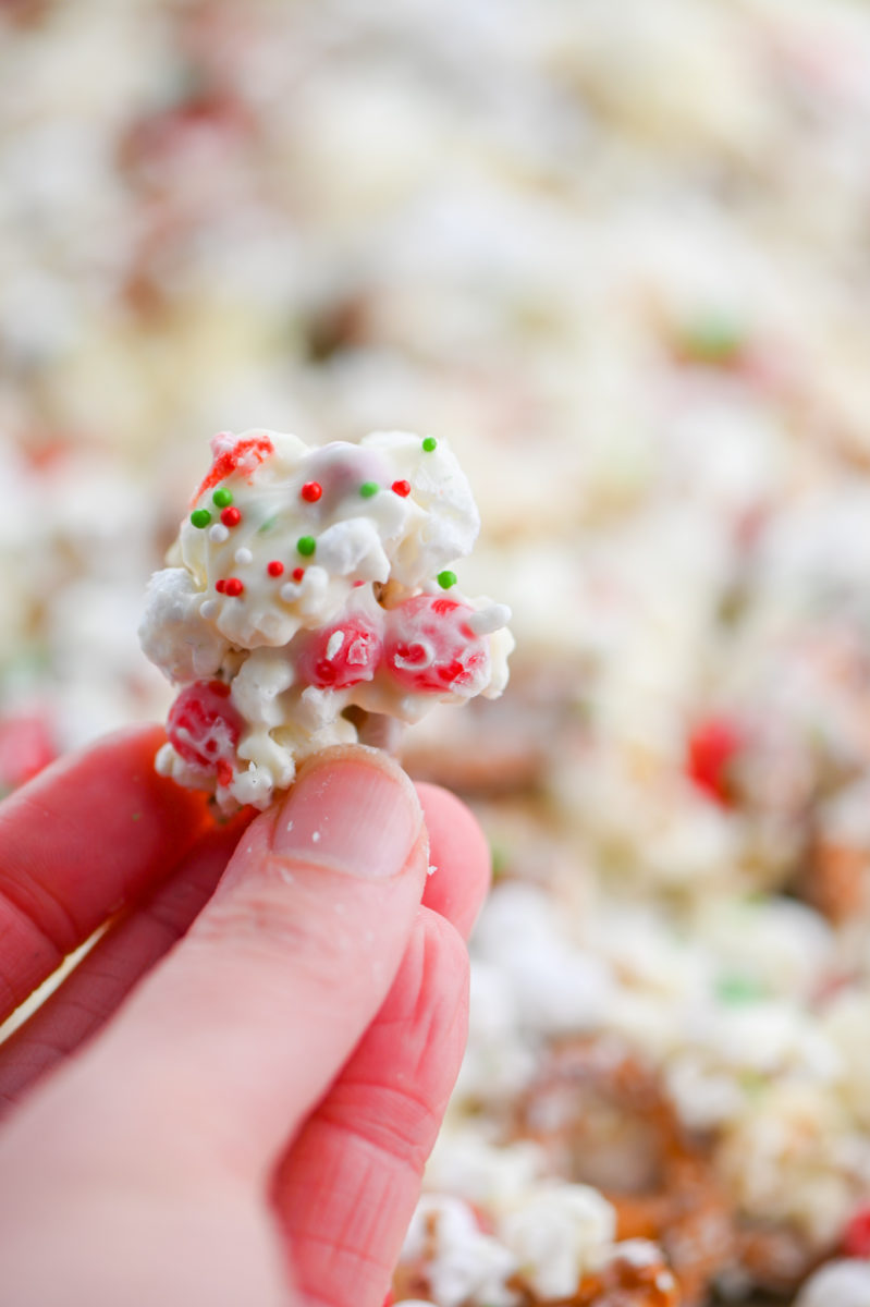 Hand holding cluster of white chocolate Christmas popcorn. 