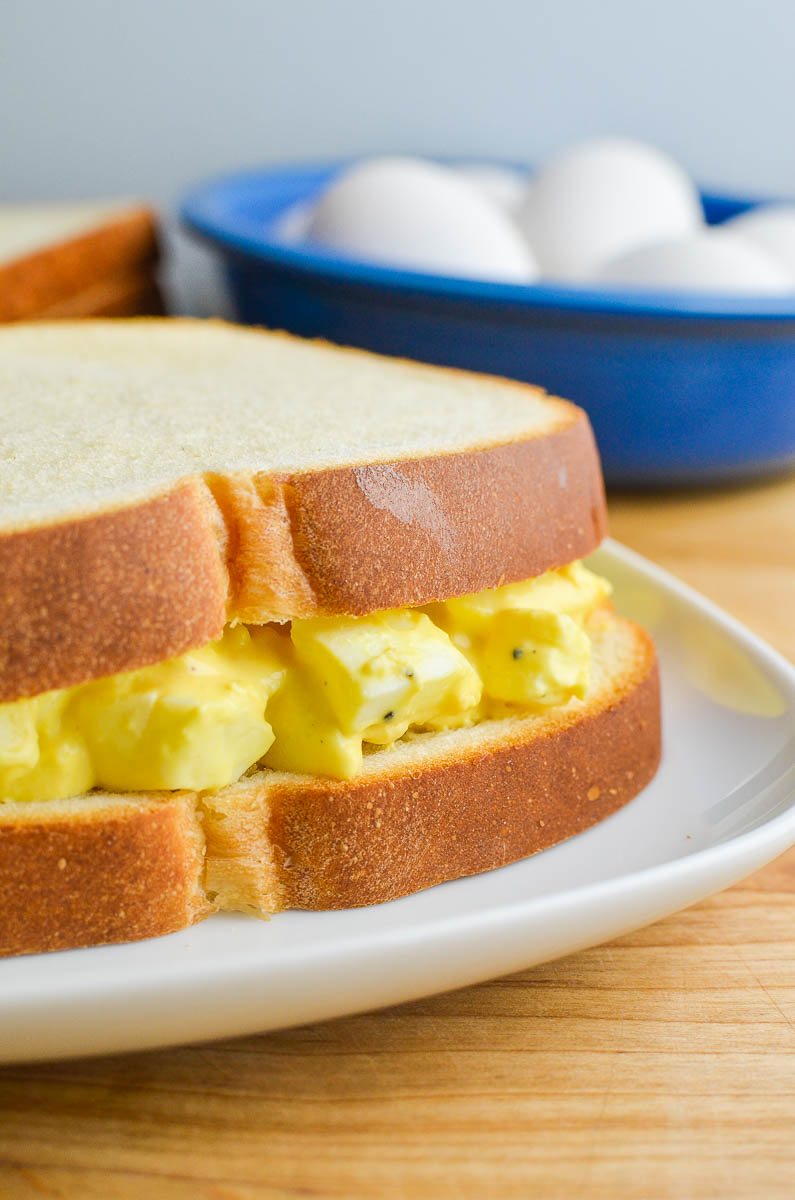 Egg salad sandwich on a white plate. 