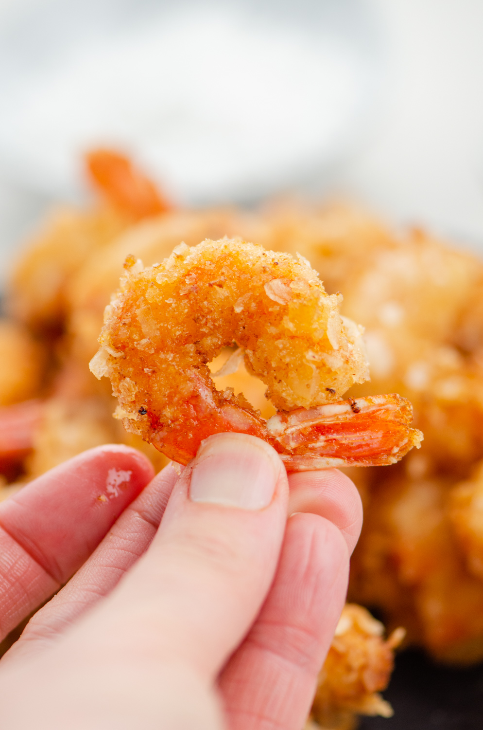 Hand holding single coconut shrimp.