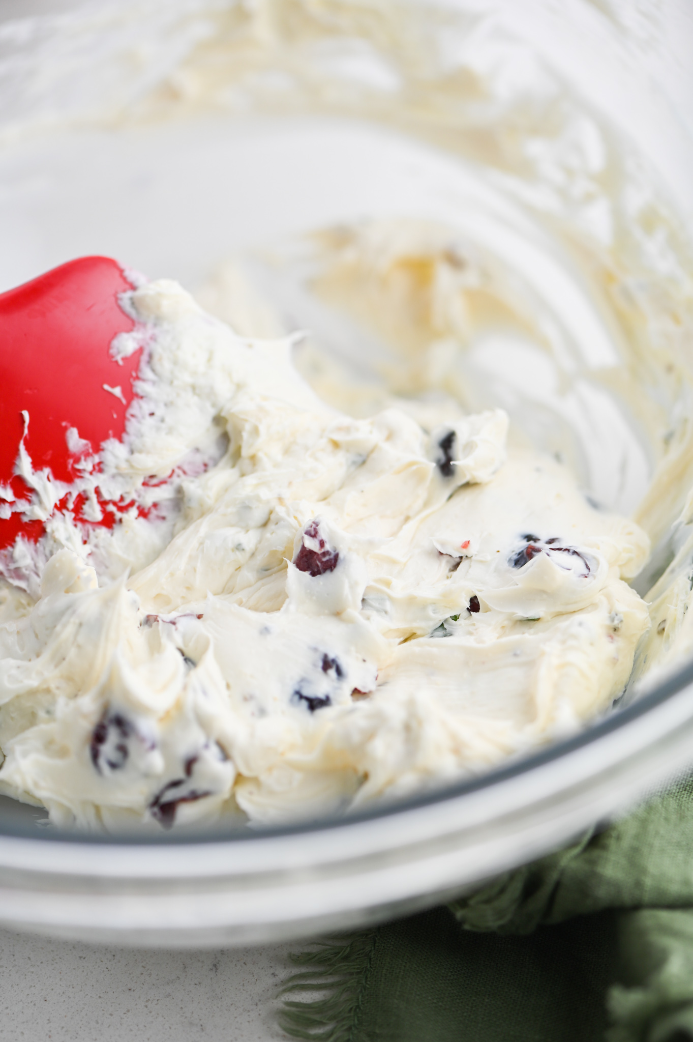 Mixing cranberry cream cheese in a glass bowl.