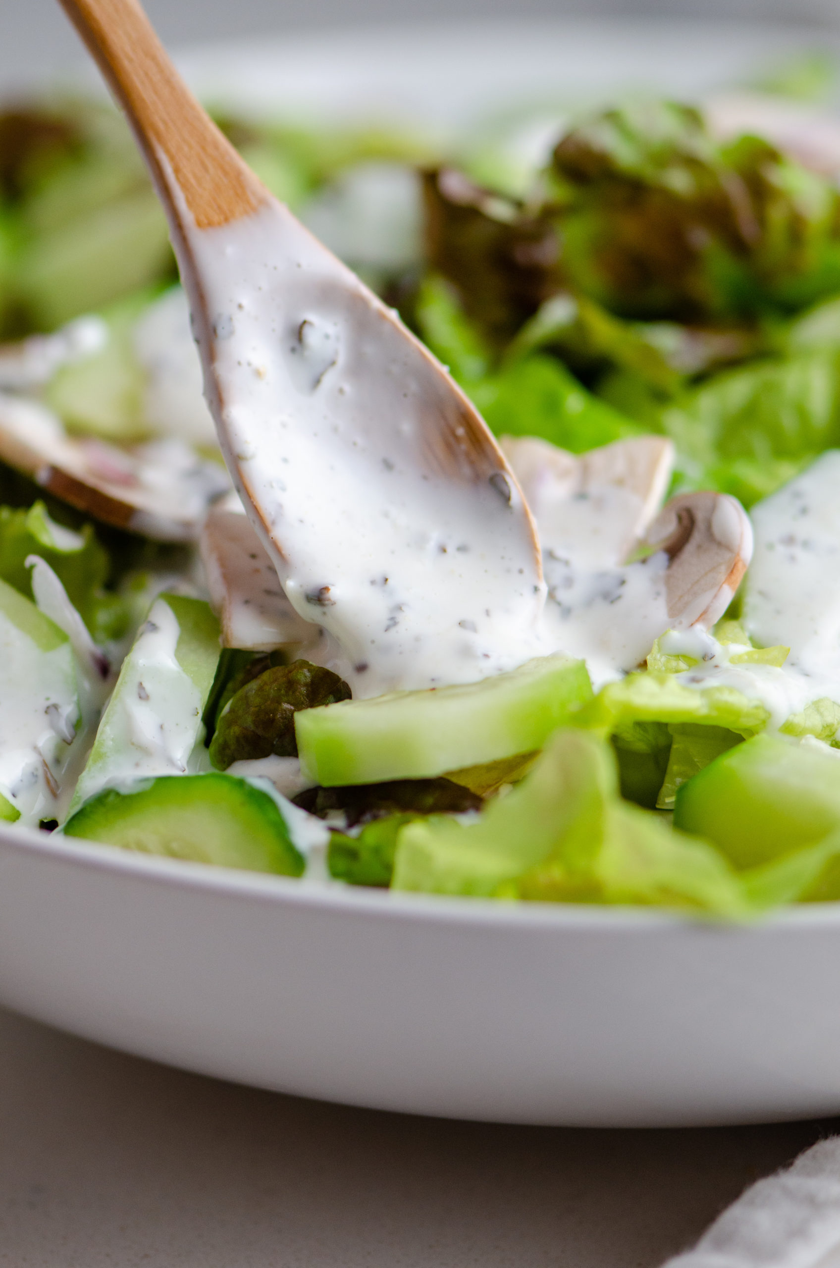 Creamy pesto dressing spooned onto salad.