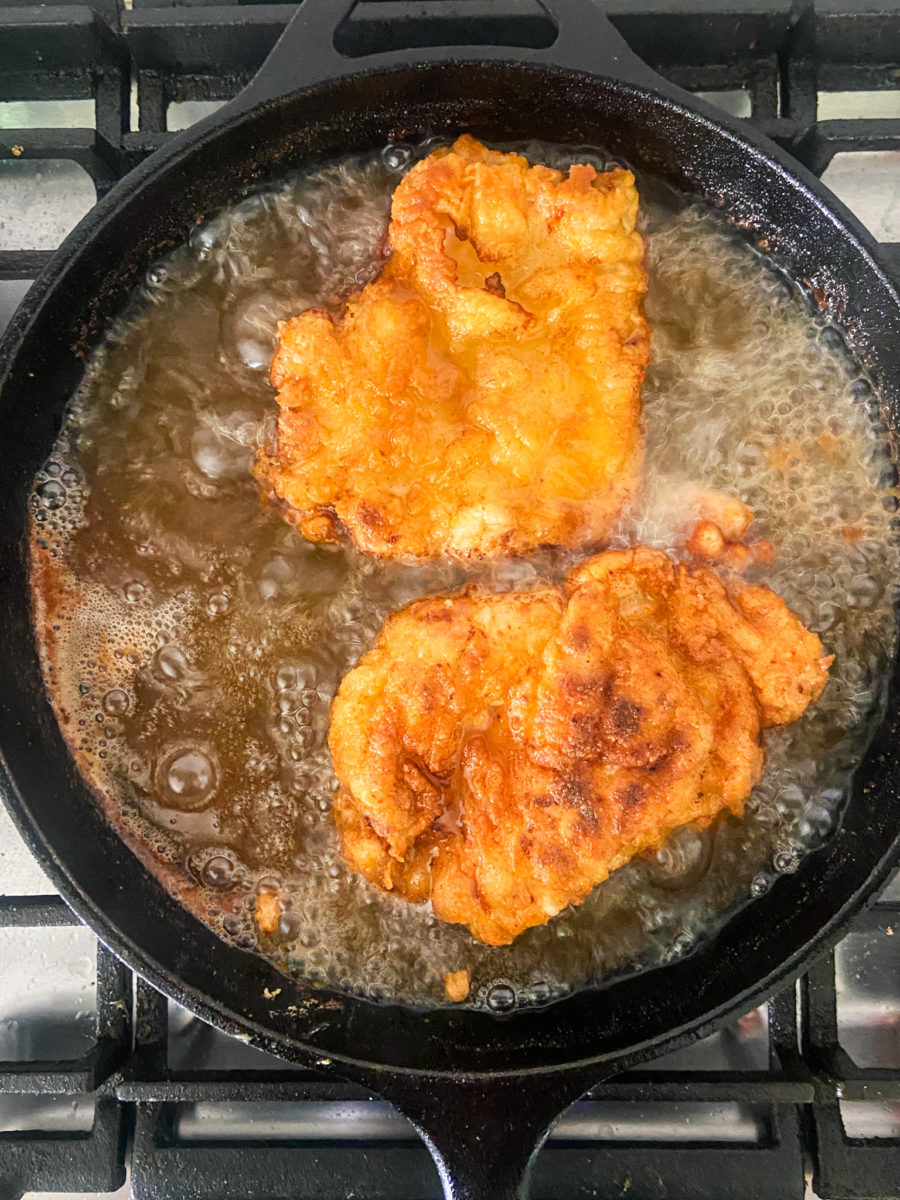 Chicken breasts frying in cast iron skillet. 