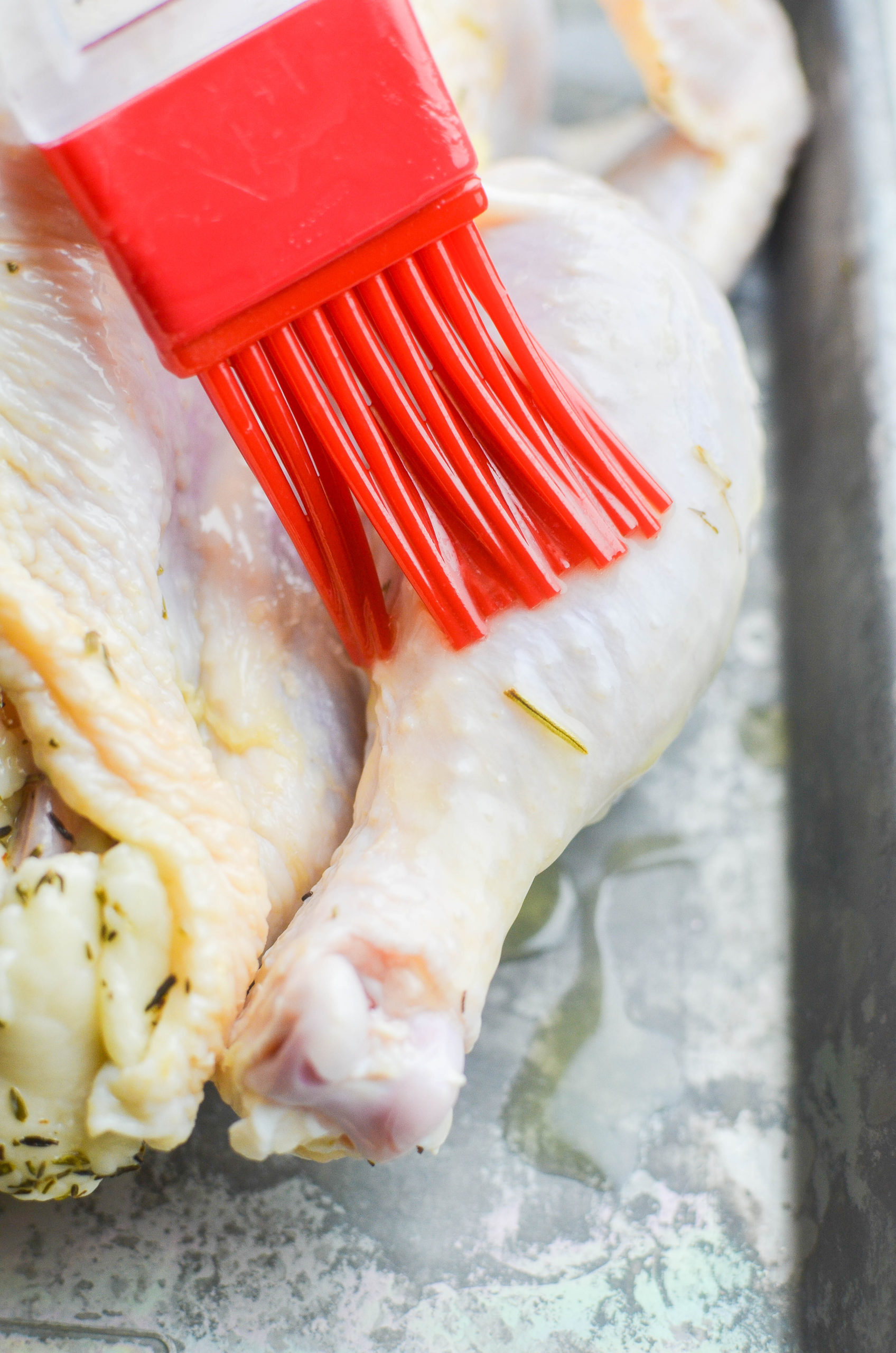 Brushing melted butter on raw chicken. 