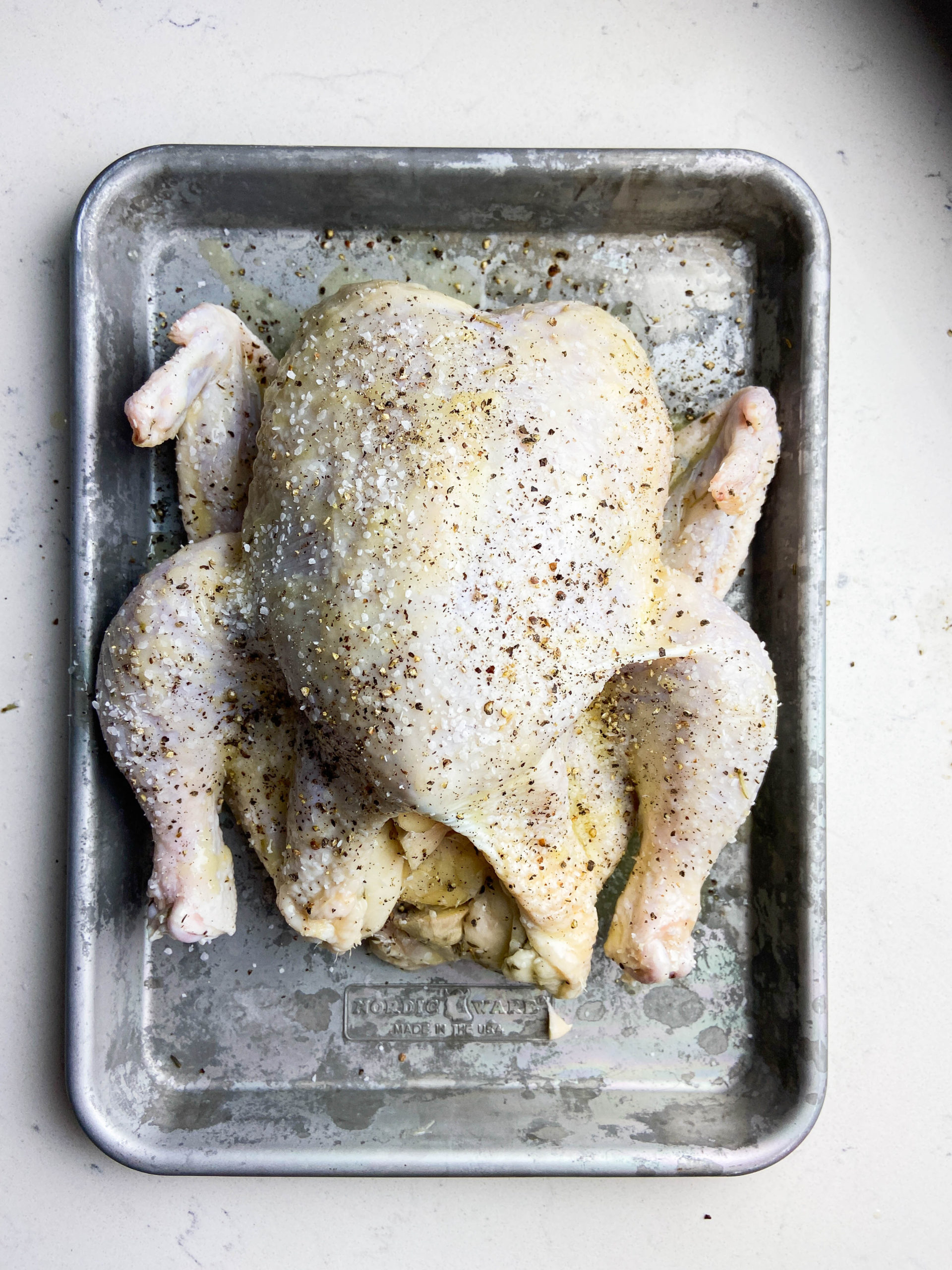 Whole chicken seasoned with salt and pepper. 