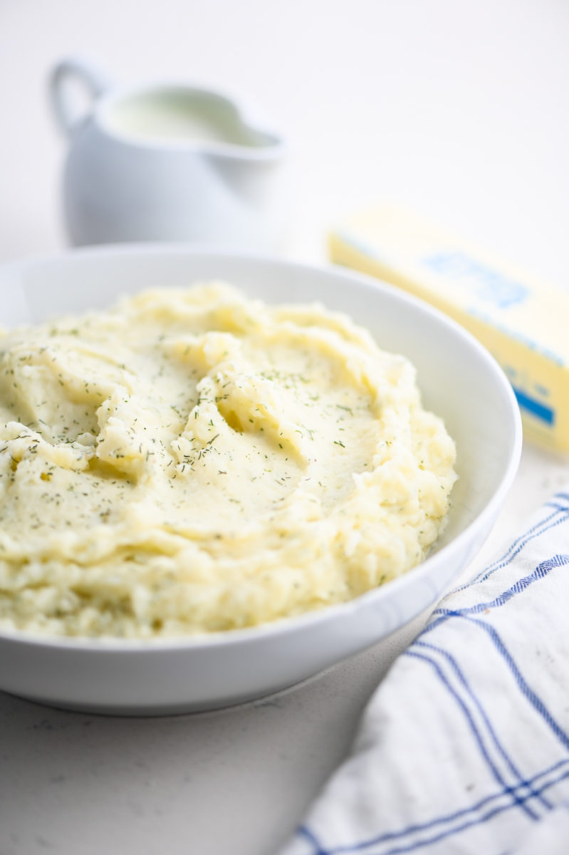 dill mashed potatoes in white bowl.